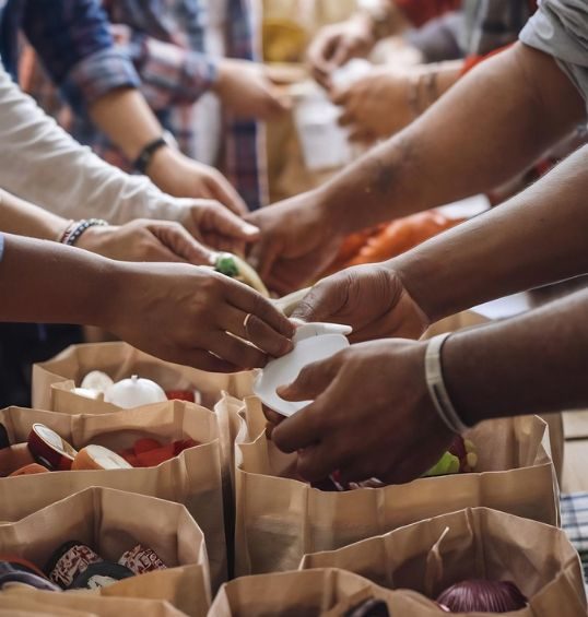 Manos entregando bolsas de alimentos como parte de una jornada de apoyo comunitario
